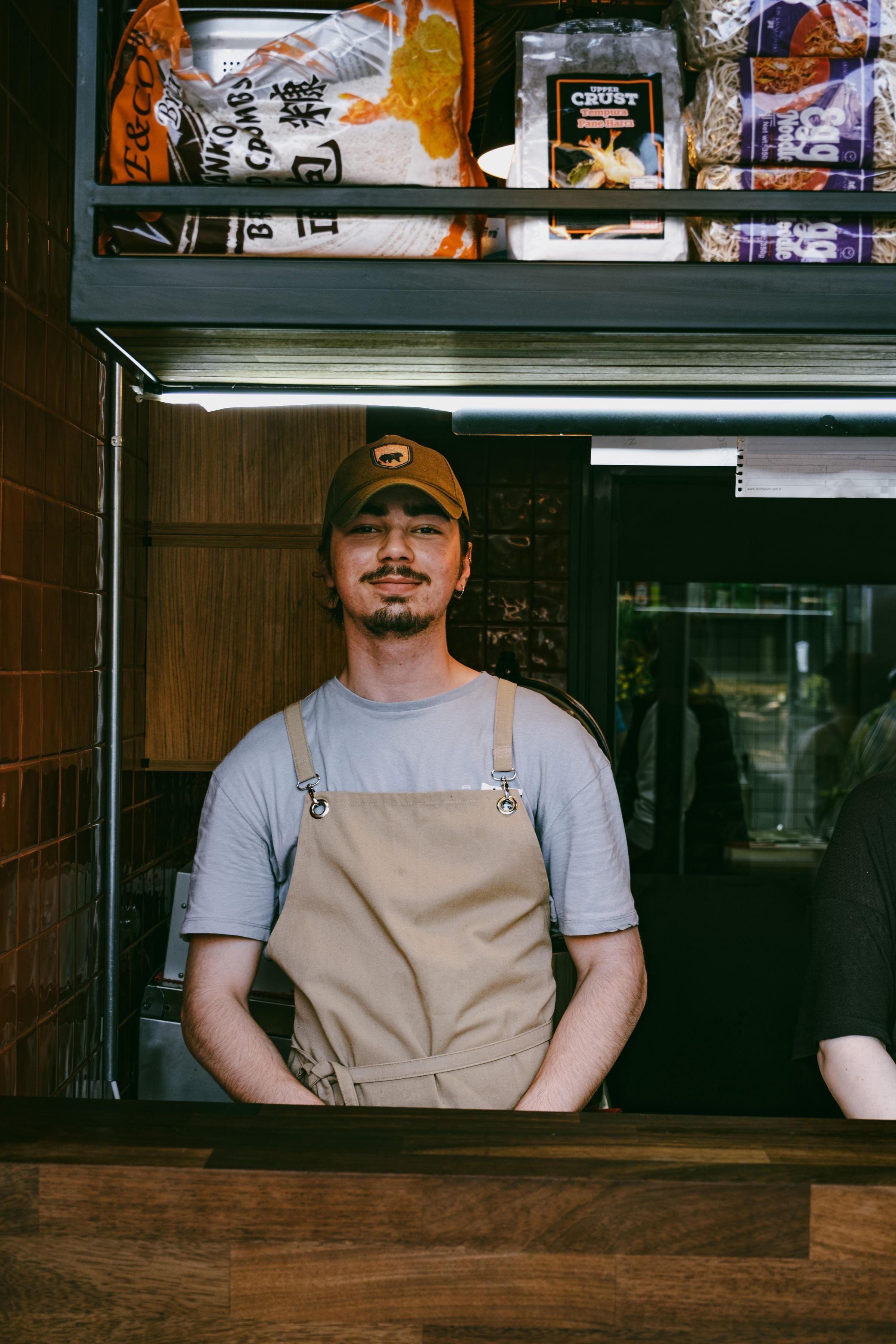 A barista in a cap and apron standing in an urban café
