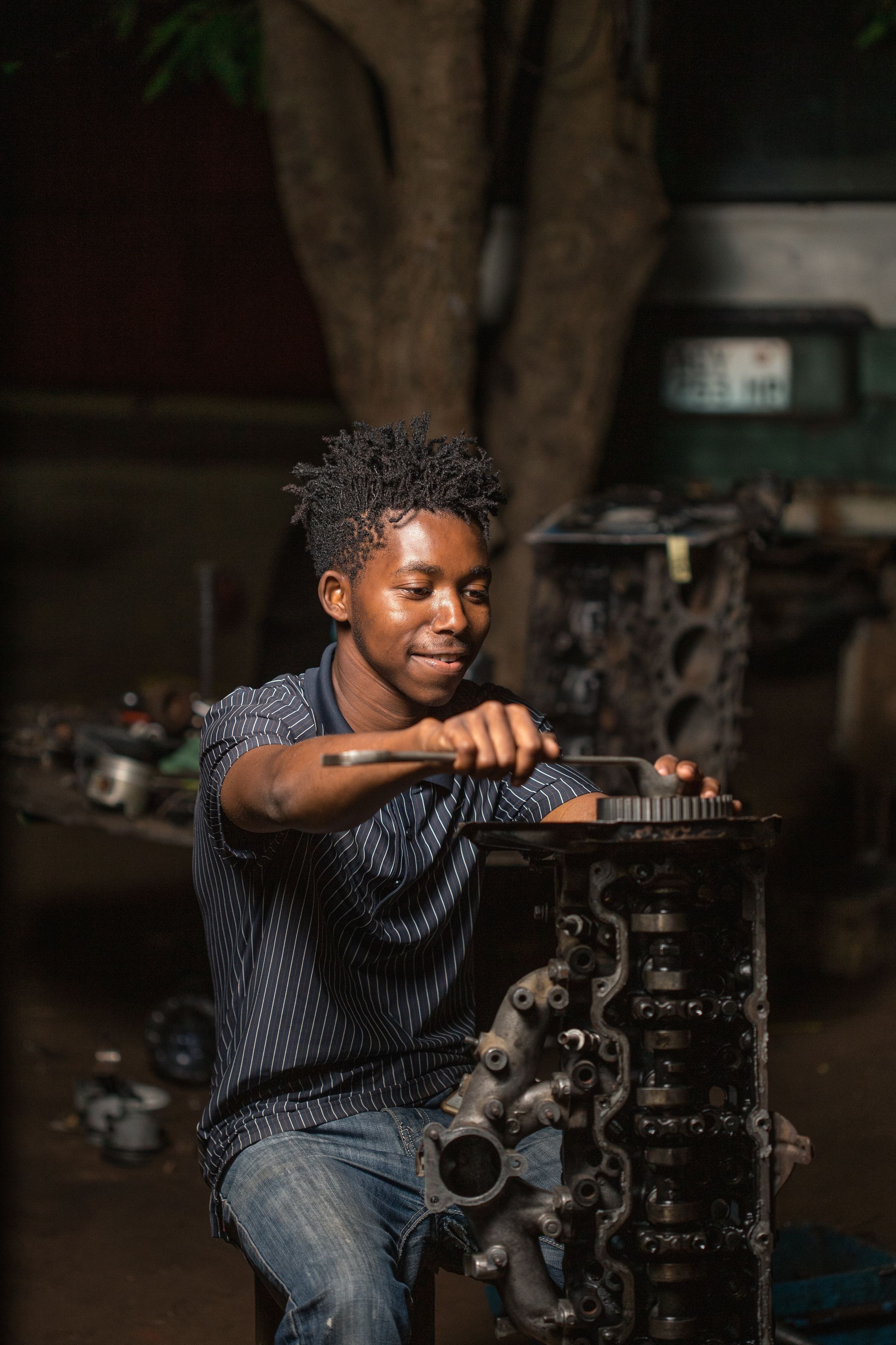 A young mechanic repairing an engine in a dimly lit workshop