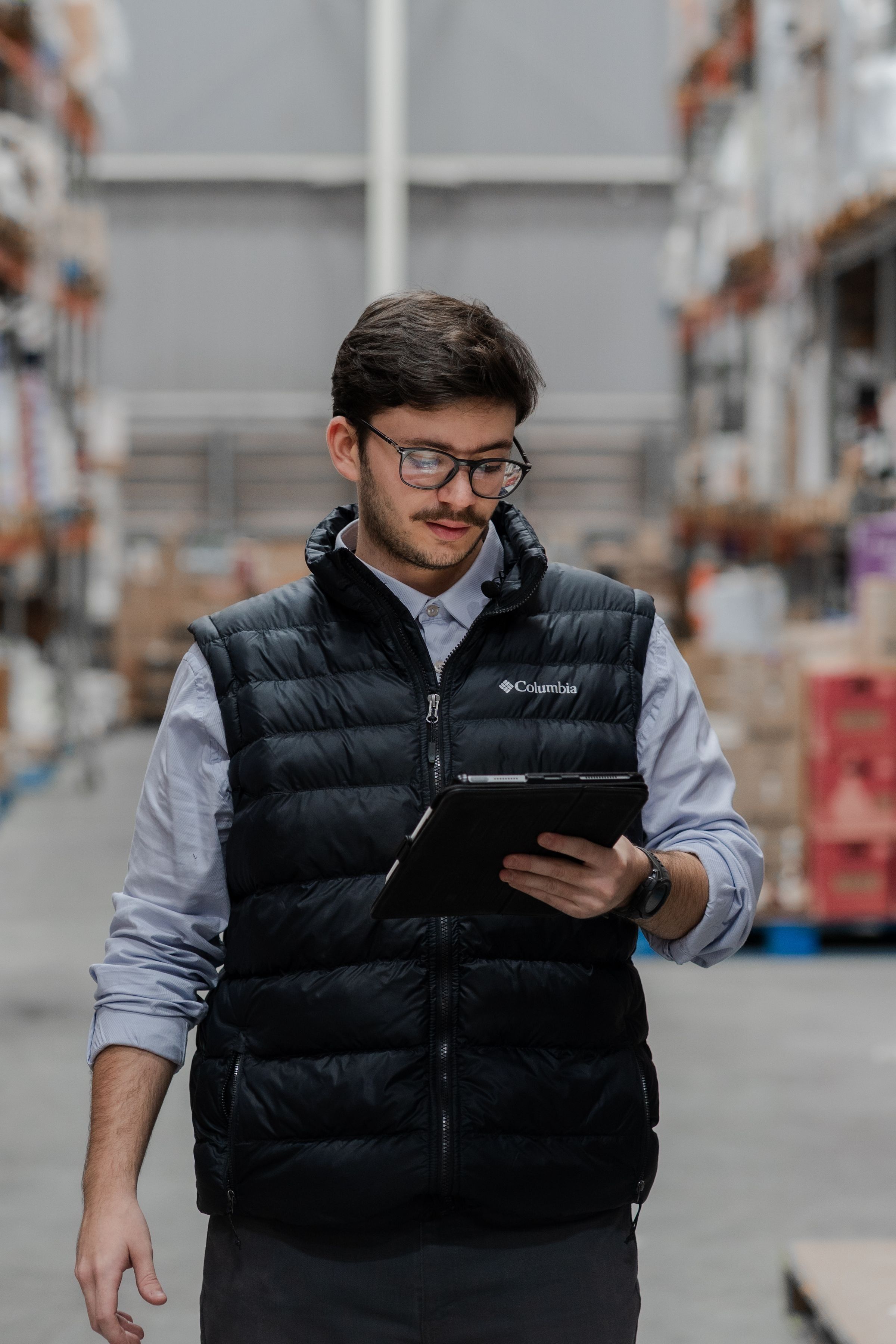 A warehouse worker checking stock on a tablet between racking