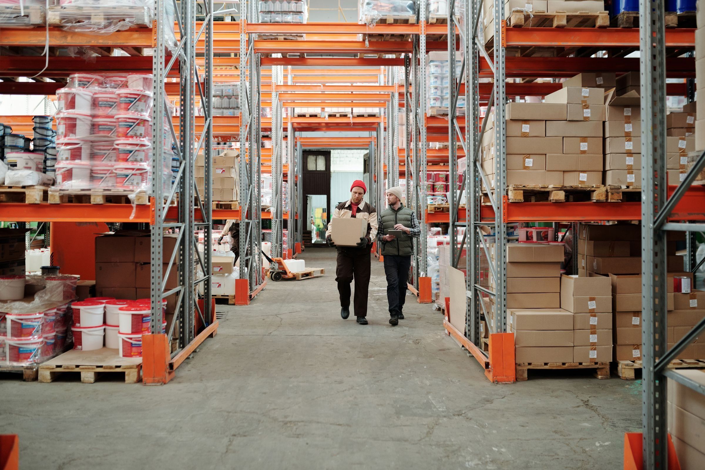 Two workers handling a package in a warehouse aisle