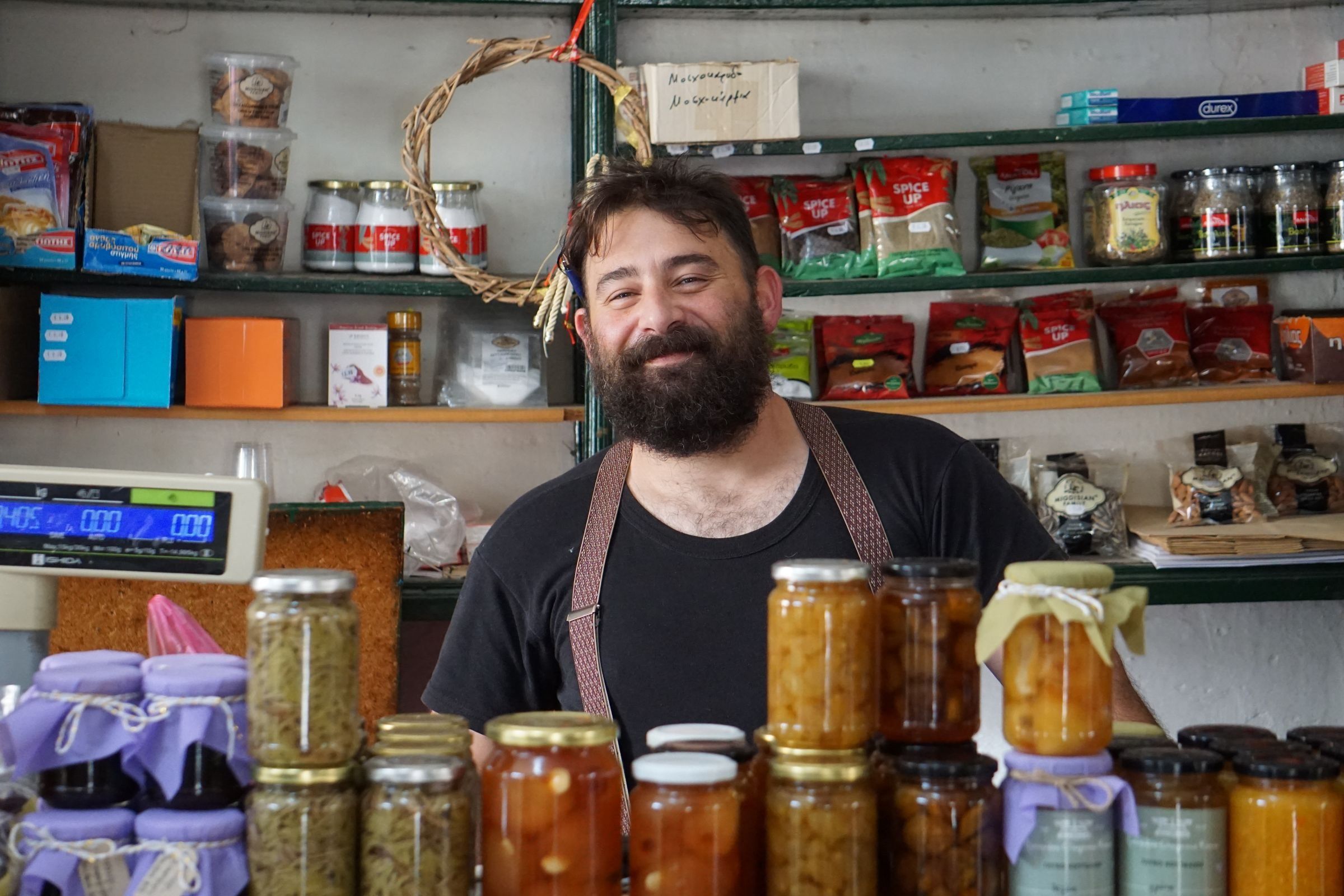 A shopkeeper standing behind shelves of homemade preserves