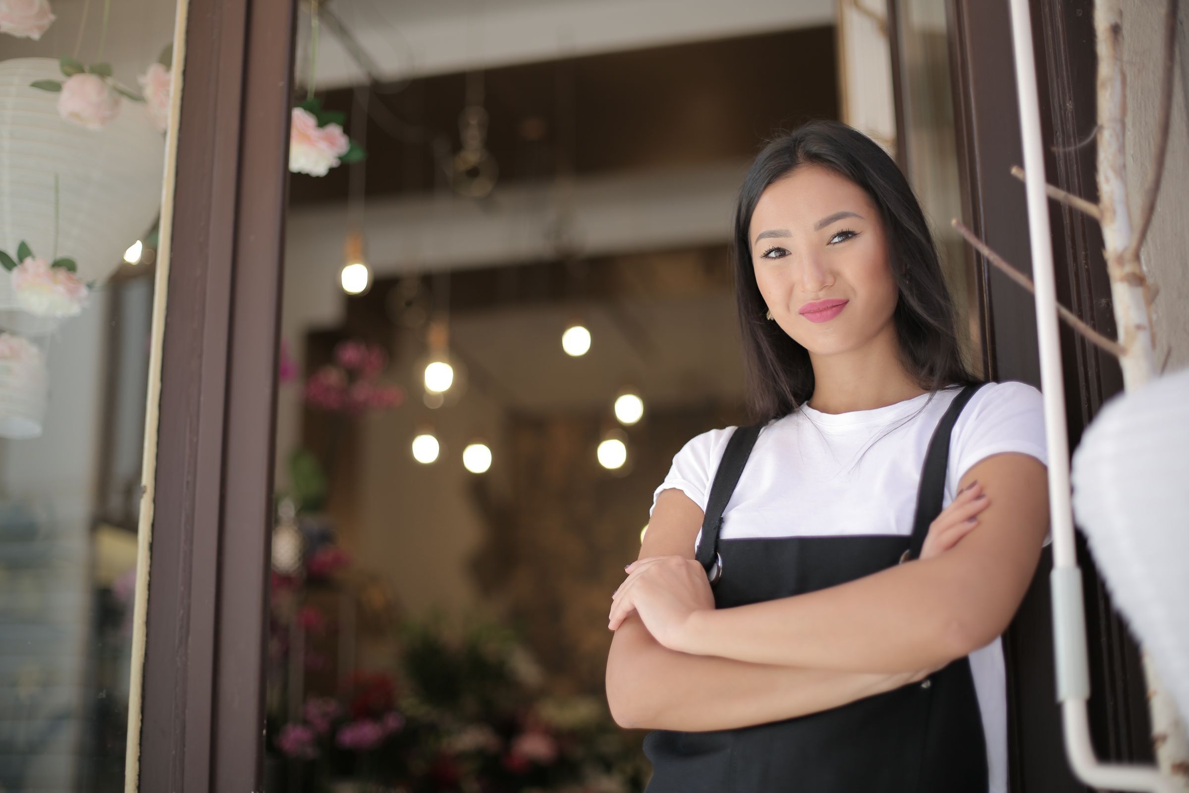 A florist standing with crossed arms at the entrance to her shop