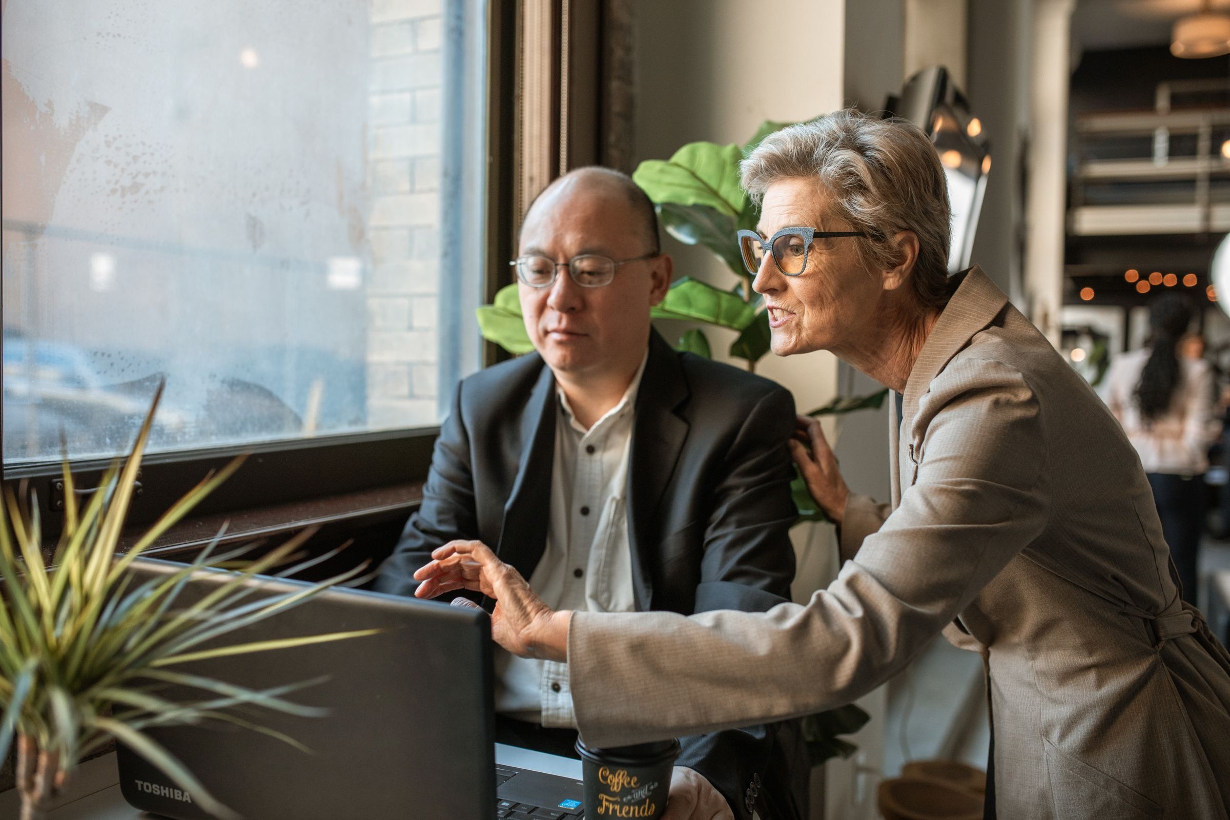 Two senior professionals discussing a project at an office desk
