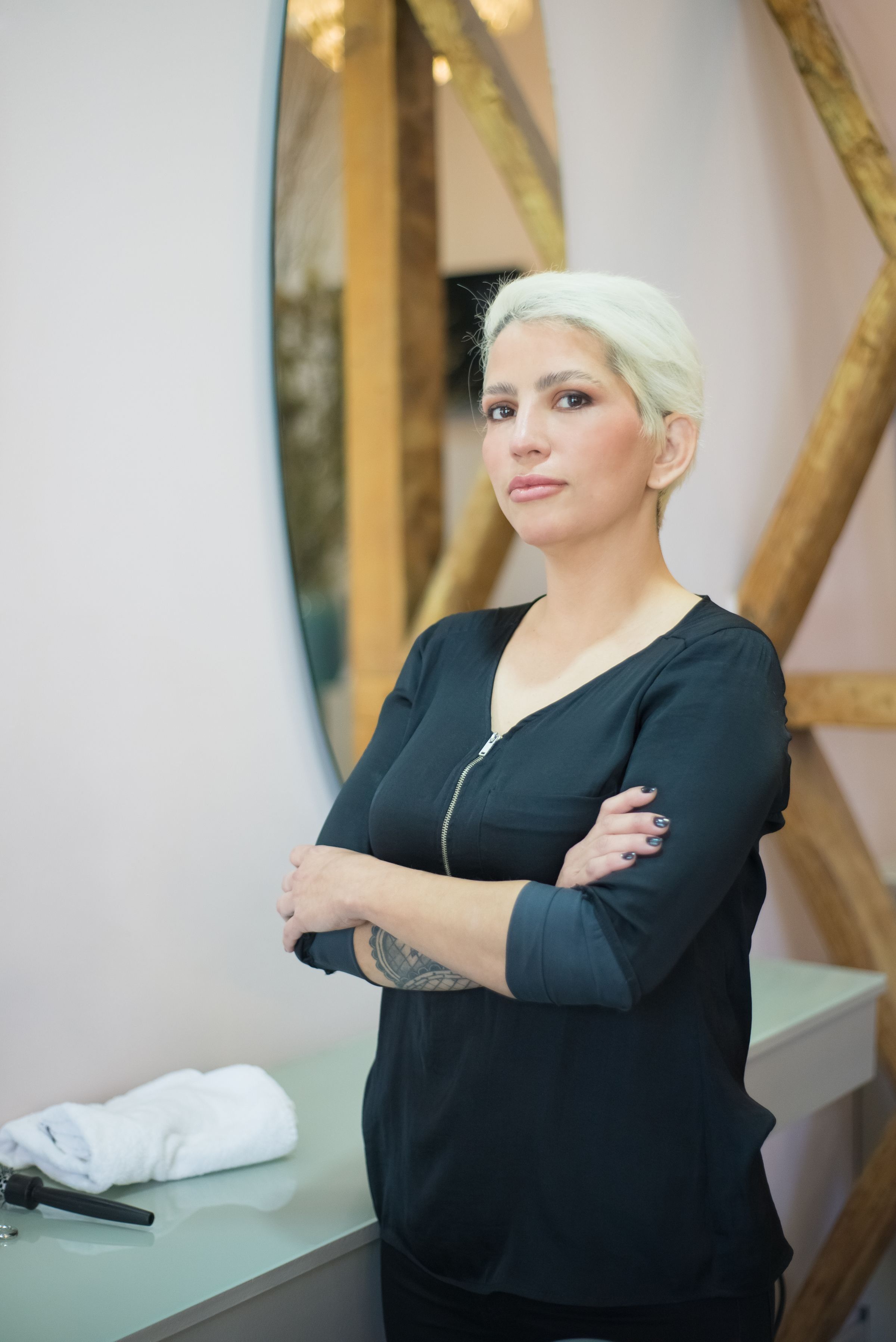 A hairdresser with folded arms standing in her salon