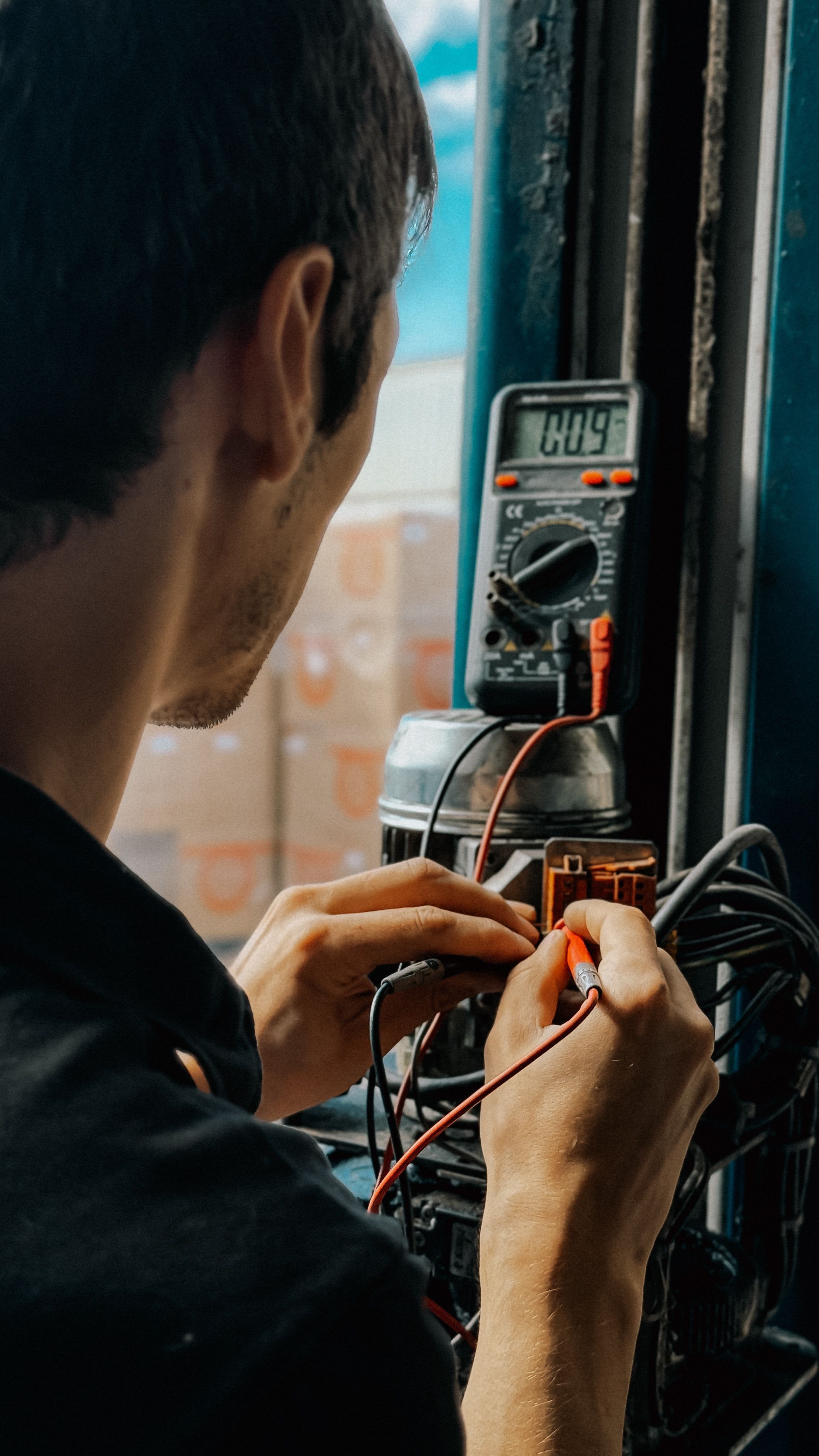 An electrician testing voltages with a multimeter in an industrial setting